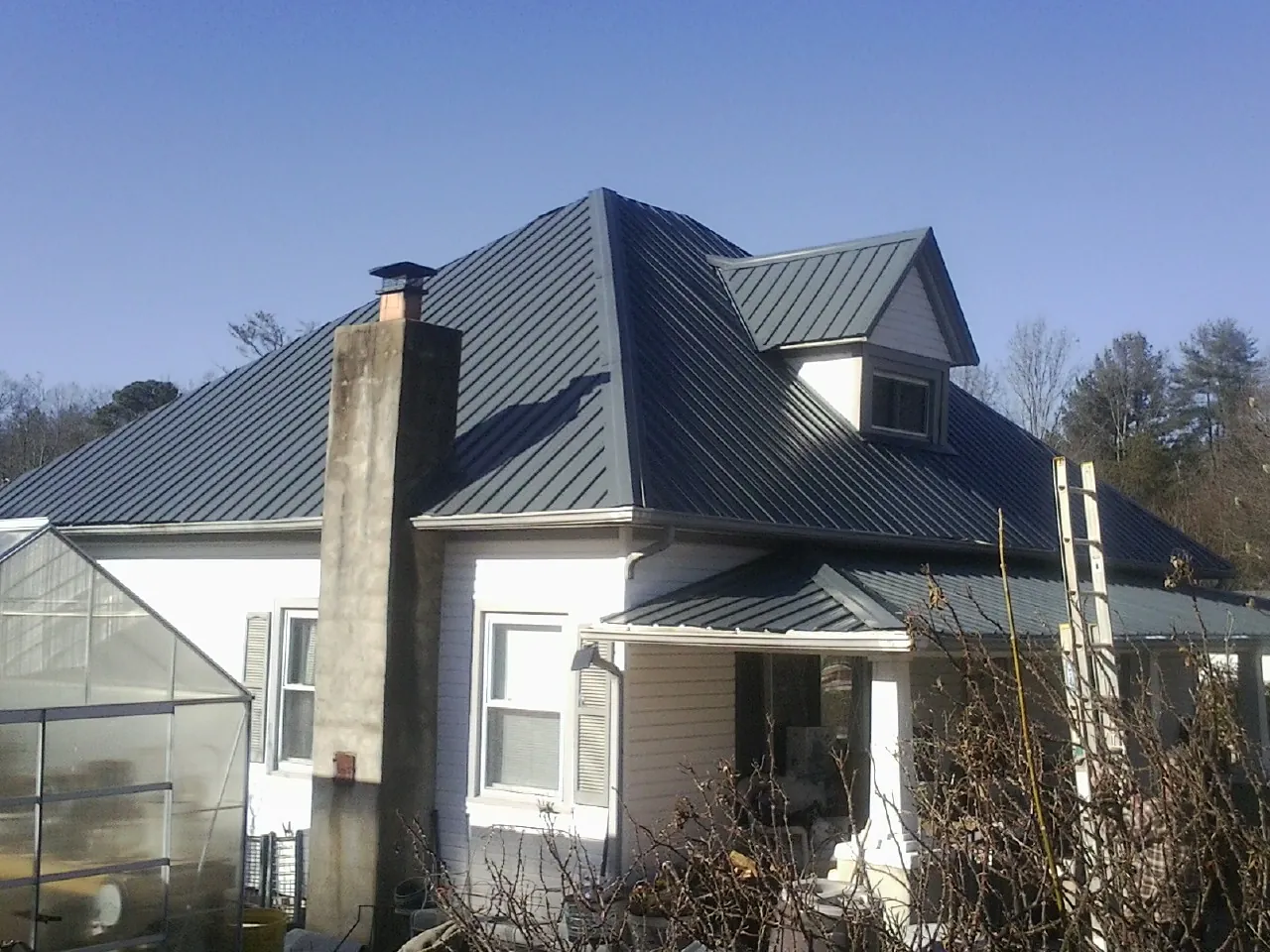 Dark blue standing seam metal roof on a white farmhouse with dormer — Slate & Tile Roof Repair by Roofing Brothers in Careywood