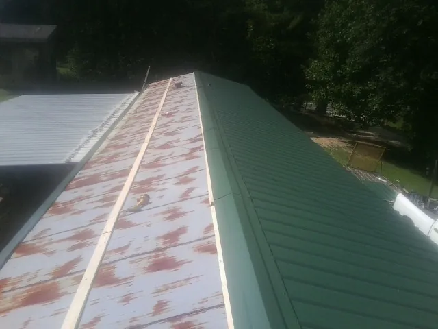 Old rusted panels beside newly installed green metal roofing — Wind Damage Roof Repair by Roofing Brothers in Careywood