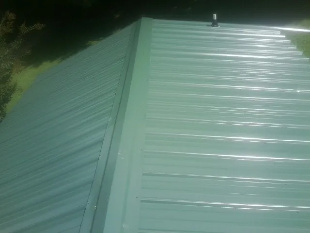 New green metal panels meeting at the ridge of a roof — Flat Roof Repair work by our crew in Careywood