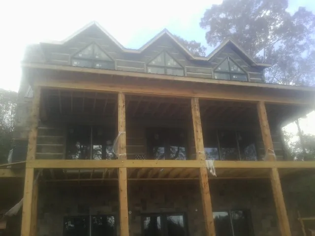 Dormers and porch framing on a large log home under construction — Roof Coating work by our crew in Careywood