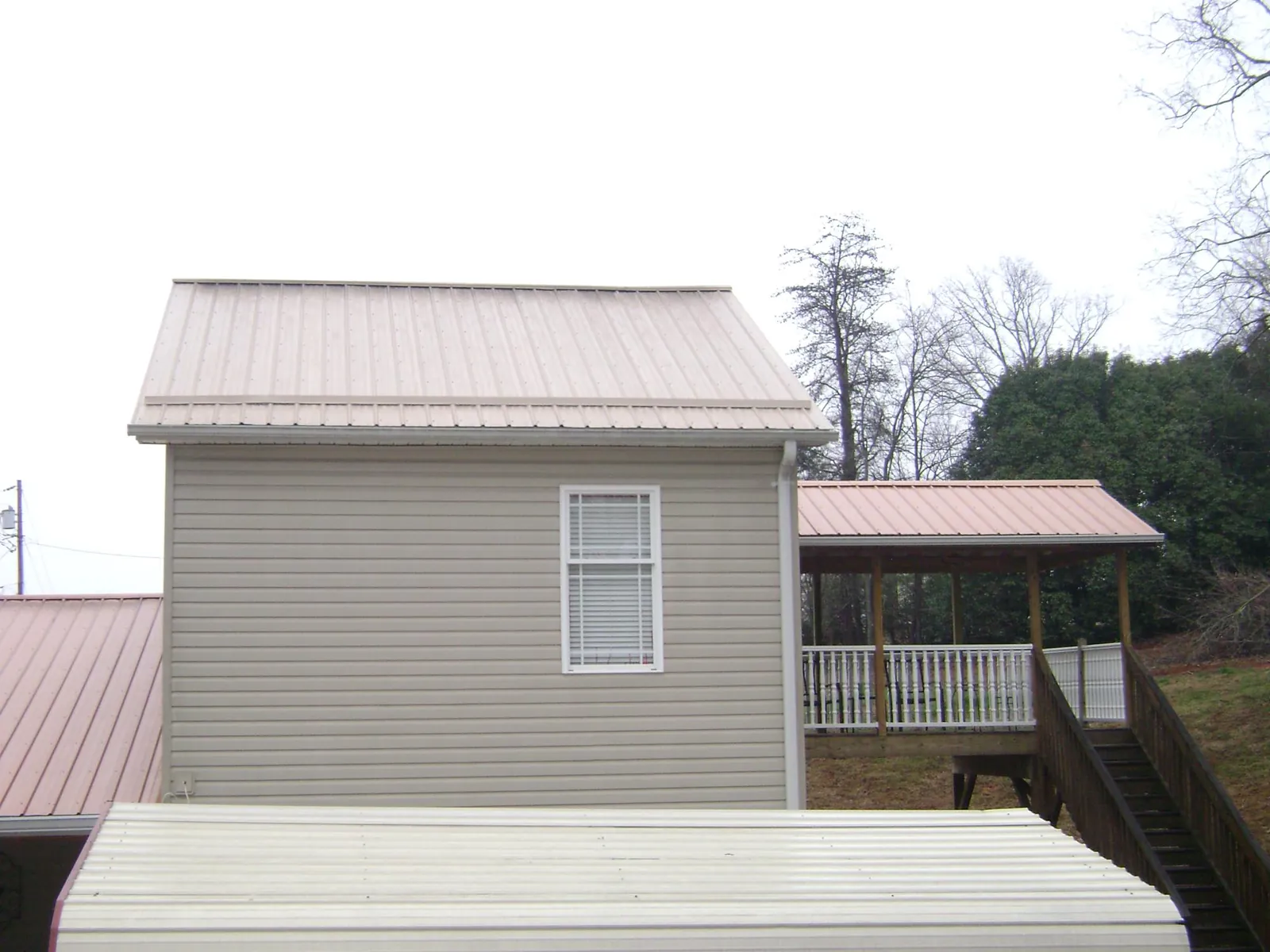 Tan metal roofs on a two story addition and attached porch, from a Roof Replacement job in Careywood