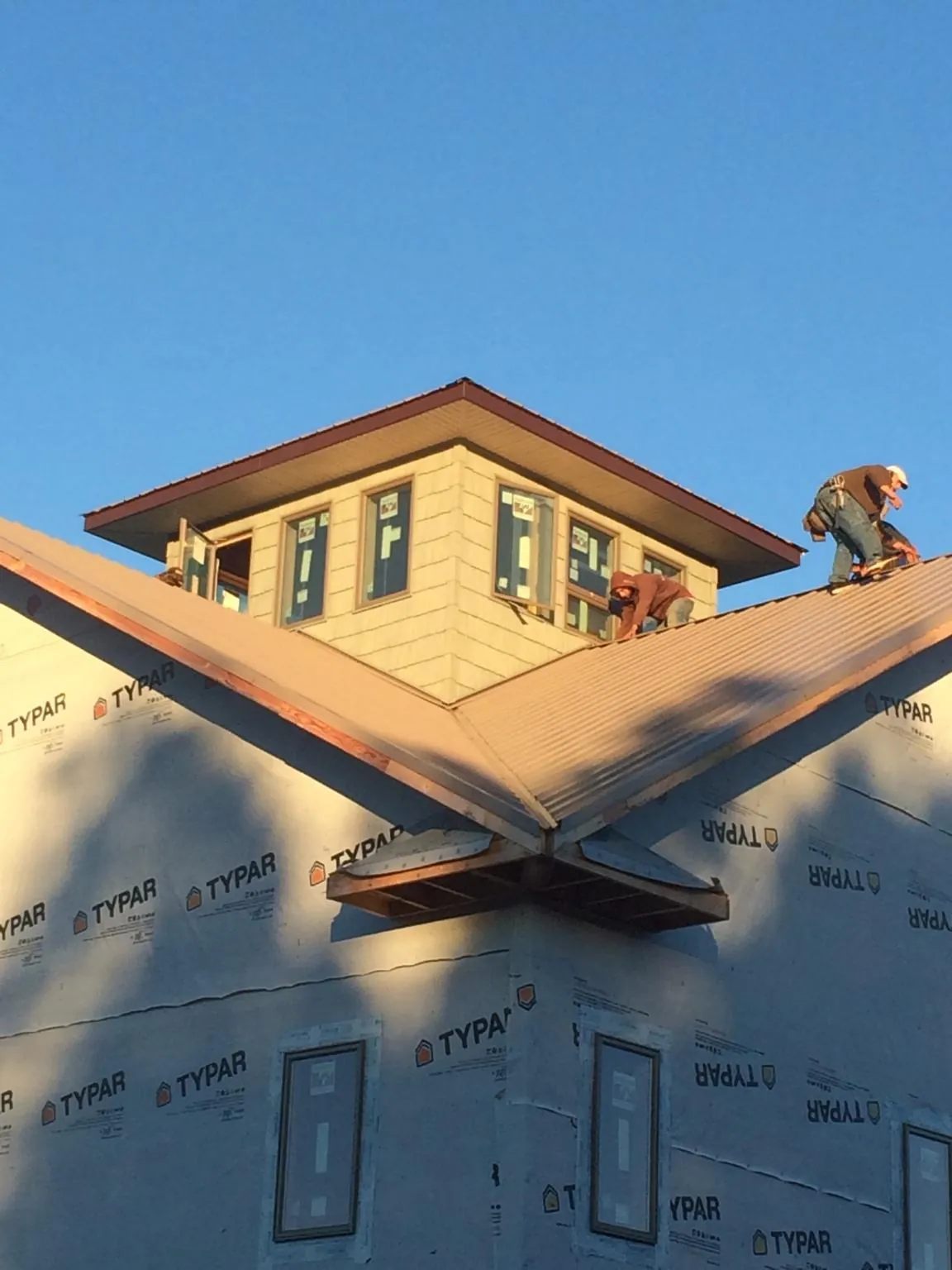 Roofers working around a rooftop cupola on a new metal roof at sunset — Roof Waterproofing in Careywood by Roofing Brothers